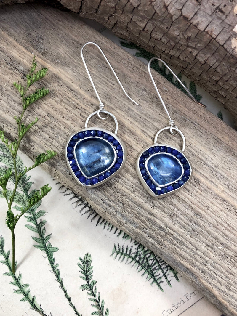 Sisters, not twins, these varying sized teardrops of flashy blue kyanite are surrounded with microfaceted lapis lazuli gemstones.  All set in sterling silver and finished on extra long French wires to give the perfect drop length.

Product Details:

• Kyanite
• Lapis lazuli gems
• Solid sterling silver
• French ear wires
