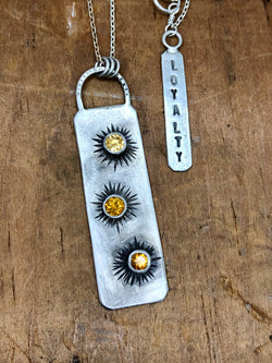 Aster

The Aster pendant and the original painting, Aster by Cathy Nichols are sold as a set.

Aster represents faithfulness to those you love, loyalty, and enduring friendship.

Three hand etched aster flowers are adorned with glowing yellow citrine centers. The silver is oxidized to show texture. At the clasp is a tag that reads LOYALTY.

"I consider each flower not just a botanical rendering, but a little portrait of the flower's unique personality." - Cathy Nichols

Original Aster 