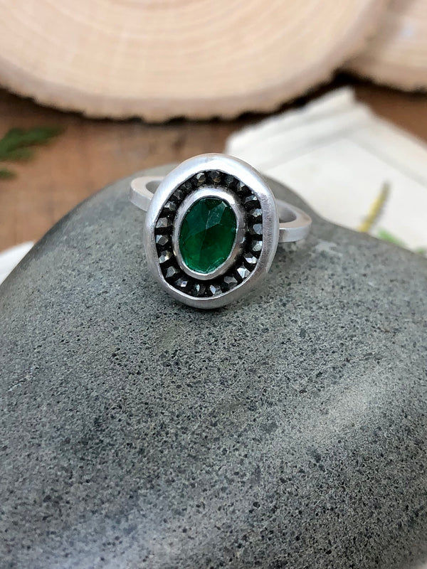 "If we have no peace, it is because we have forgotten that we belong to each other." - Mother Teresa

A lovely forest green oval emerald is surrounded by a halo of pyrite gemstones.  All set in sterling silver and size 5. 

Product Details:

• Oval faceted genuine emerald
• Faceted pyrite gems
• Sterling and fine silver
• Square ring shank in size 5