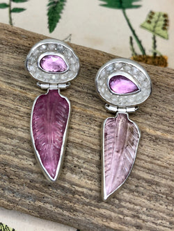 Winter’s slumber gives way to the chaos of emergent spring.

Rest easy as translucent carved pink tourmaline “feathers” sweep in the most pleasant dreams just for you. Supported on tiny hand-fabricated silver hinges, they swing from pink sapphires graced with a halo of micro-faceted quartz crystal gems. 

• Rose cut pink sapphires
• Carved pink tourmaline
• Micro-faceted quartz crystal gems
• Fine and sterling silver
