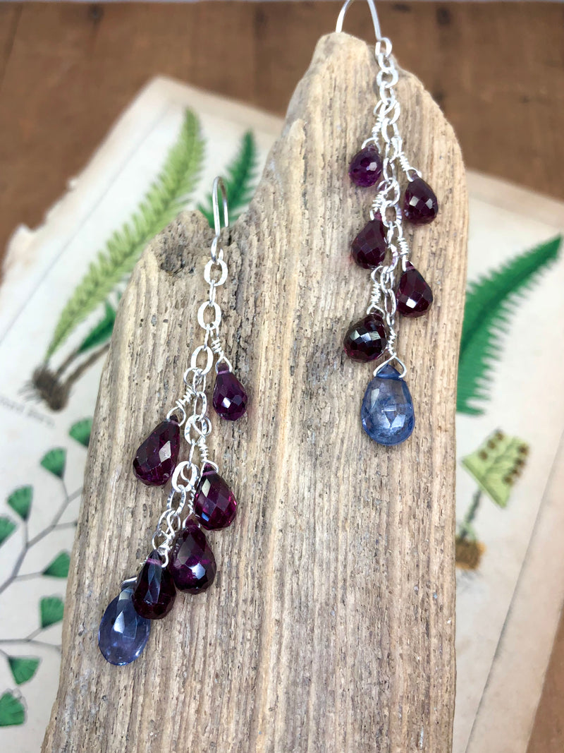 Perfectly crimson rhodolite garnets are displayed on fancy silver chain with a beautiful iolite gem at their focal point. Approximately 2.5” from the hook and finished on sterling French wires.

• 8 - rhodolite garnet briolettes 
• 2 - iolite briolettes 
• Fancy silver chain
• Sterling French wires
