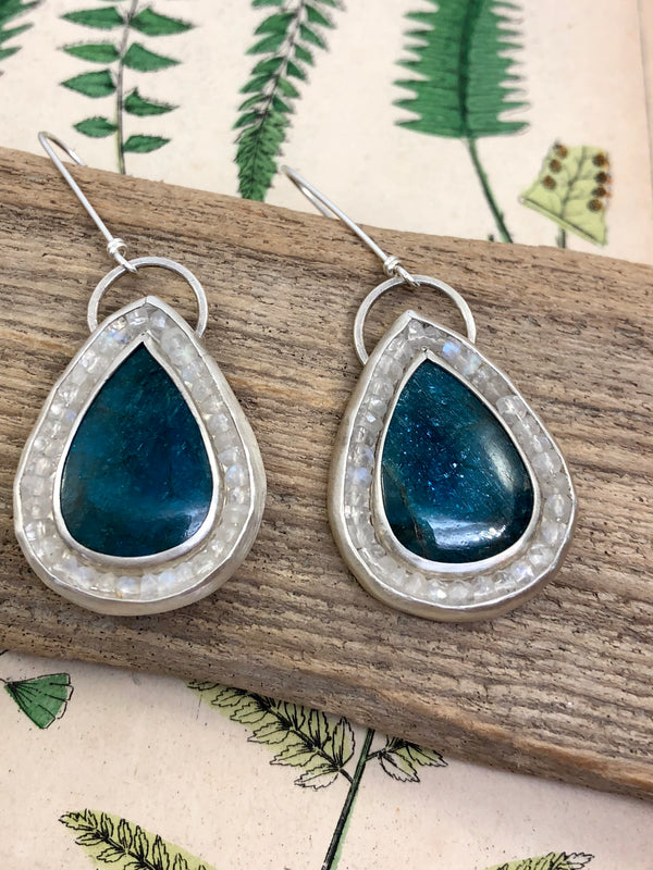 Embrace all the wonder and enchantment that comes with spring.

Meditate on the clarity of these radiant drops of pristine blue-green apatite to clear away any apathy or confusion. Perfectly supported with brilliant rainbow moonstones, these beacons of light call to mind the promise of Spring’s new beginning. Wear them all year ‘round to inspire new projects, acts of compassion, and your very best self. 

•Apatite gems
•Rainbow moonstone gems
•Extra long French ear wires
•Fine and ster