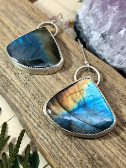 "Compassion is an action word with no boundaries" - Prince

Lose yourself in dreamy layers of blue and amber. Rich and subtle Labradorite gems are expertly displayed in a completely hand-fabricated setting with tiny serrated edges.Wide tear-drop forms are finished on extra long wire-tied French wires. 

Product Details:

• Extra-long sterling silver ear wires
• Two Labradorite Gems
• Sterling and fine silver
• Approximately 2" long and just over 2.5" long from the top of the French wir