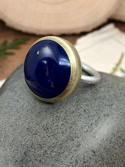 A high quality, round lapis gem is surrounded by a brass bezel and set on sterling silver band. Size 6. 

Product Details:

• Lapis lazuli cabochon
• Hand-forged brass
• Sterling silver
• Size 6