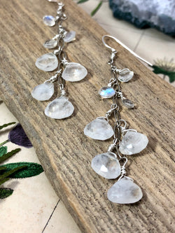 "Love and compassion are necessities, not luxuries. Without them, humanity cannot survive." - Dalai Lama XIV

Bask in the gentle glow of Rainbow Moonstone drops. Graduated in size, each unique stone gathers and refracts light. Subtle hints of color shine from pear-shaped and faceted gems. Gems are wire wrapped and arranged along silver chain. They are finished on standard French wires. A cascade of light and color perfect for any elegant casual ensemble.

Product Details:

• Sterling s