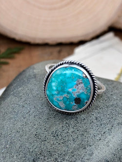 "We must learn to regard people less in the light of what they do or what they omit to do, and more in the light of what they suffer." - Dietrich Bonhoeffer

Each time you gaze at the turquoise gem in this ring, you will be pulled in further and further by its natural blue and white pools and pyrite inclusions. Mother Earth has done it again with this incredible gem from the Whitewater Turquoise mine. Elegantly set in sterling and fine silver with a diainty twisted wire halo and finish